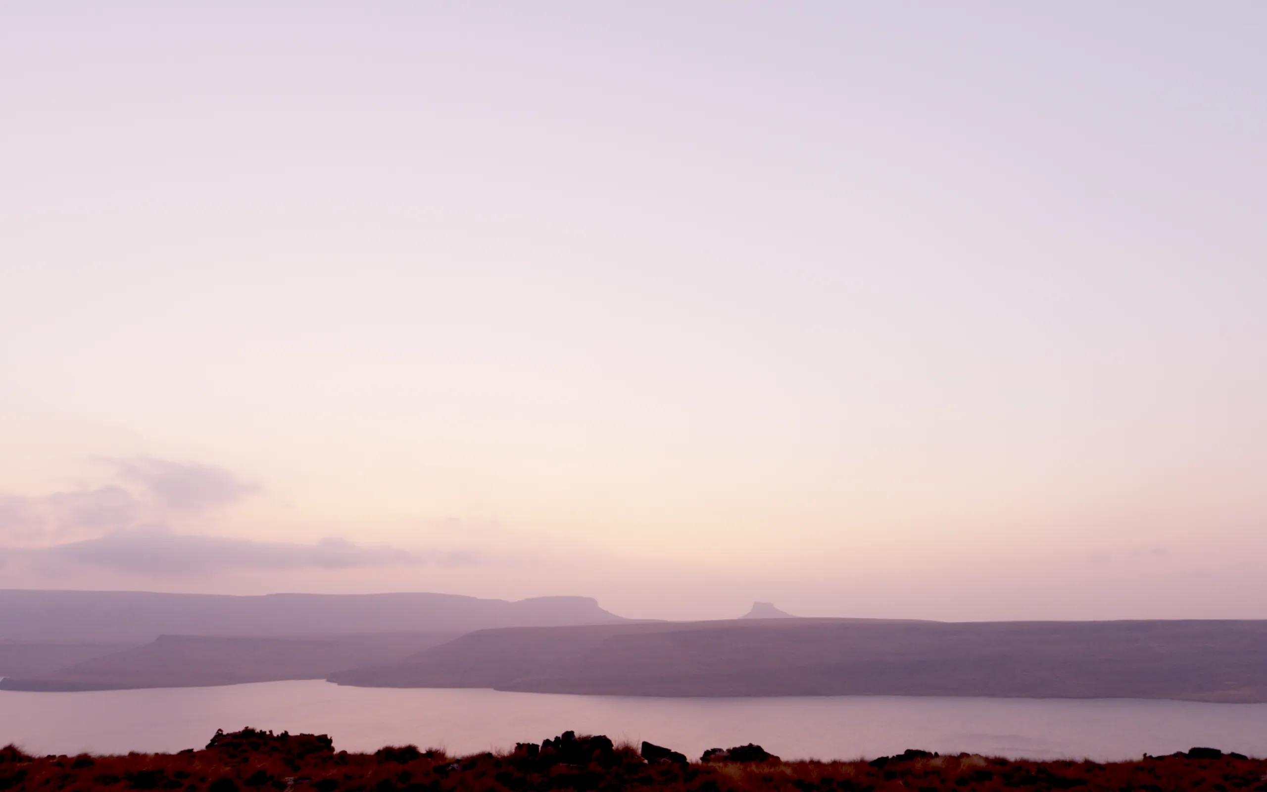 Dusk: mauve sky, a few lit clouds, the first lights of the town along the far shore.